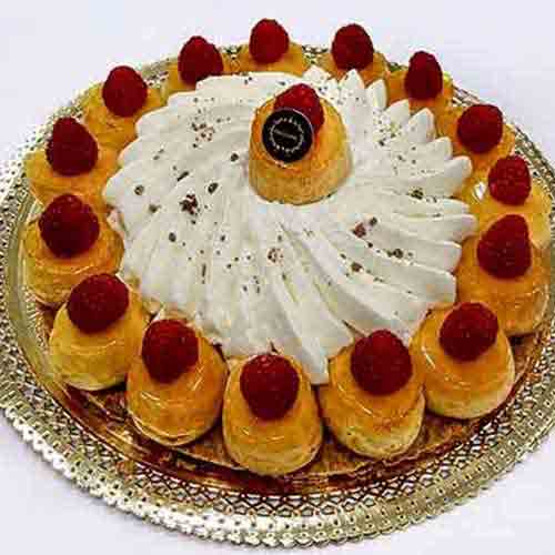 Uma sobremesa decorativa com natas, folhados de massa folhada cobertos com framboesas e um remoinho de chantilly, dispostos numa travessa de prata - perfeita para bolos de frutas.