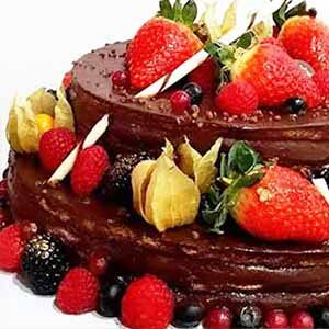 Um bolo de chocolate de duas camadas dos bolos da Pâtisserie Dacquoise, decorado com morangos, framboesas, amoras, groselhas, groselhas do cabo e pedaços de chocolate branco, é apresentado num fundo branco como numa galeria.