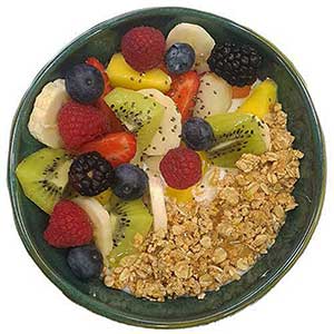 Uma taça verde cheia de granola, fruta fresca e sementes de chia sobre iogurte.