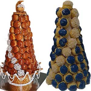 São apresentadas duas torres altas de croquembouche em forma de cone. A torre da esquerda é vidrada a caramelo com apontamentos decorativos brancos, enquanto a da direita apresenta croquembouche e amarelos com cachos de pérolas brancas, evocando a elegância dos bolos da pastelaria fina.