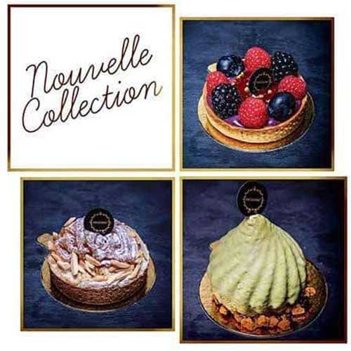 Uma seleção de pastelaria elegante e moderna das nossas Coleções Sazonais com acabamentos brilhantes e logótipos decorativos de chocolate, dispostos sobre um fundo escuro com flores brancas em primeiro plano.