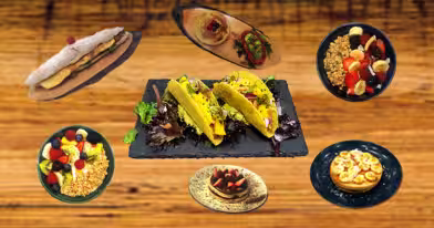 Menus Dacquoise Uma mesa de madeira exibe vários pratos: tacos numa travessa de ardósia no centro, rodeados por taças de fruta e granola, uma tarte de sobremesa, Saladas dacquoise, mousse de chocolate, um crepe e um prato com uma massa com cobertura de fruta.