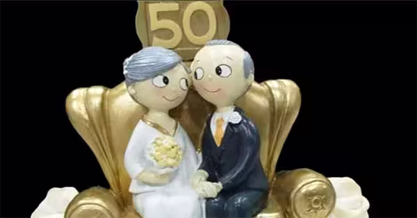 bodas de ouro. vê-se um casal muito chique sentado num sofá dourado com a imagem dos 50 anos de casados