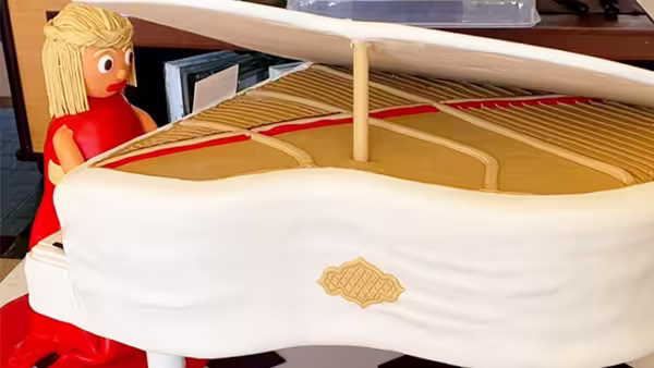 Uma mulher vestida de vermelho toca um piano de cauda branco. Bolo perfeito para um casamento