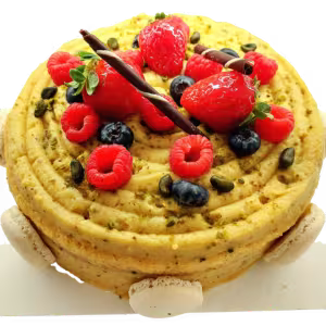 Bolo sem gluten. Redondo com um desenho em espiral, coberto com frutos vermelhos frescos, sementes de abóbora, palitos de chocolate e merengues. Delicie-se com esta criação da nossa linha de bolos sem glúten