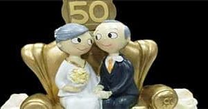 bodas de ouro. vê-se um casal muito chique sentado num sofá dourado com a imagem dos 50 anos de casados